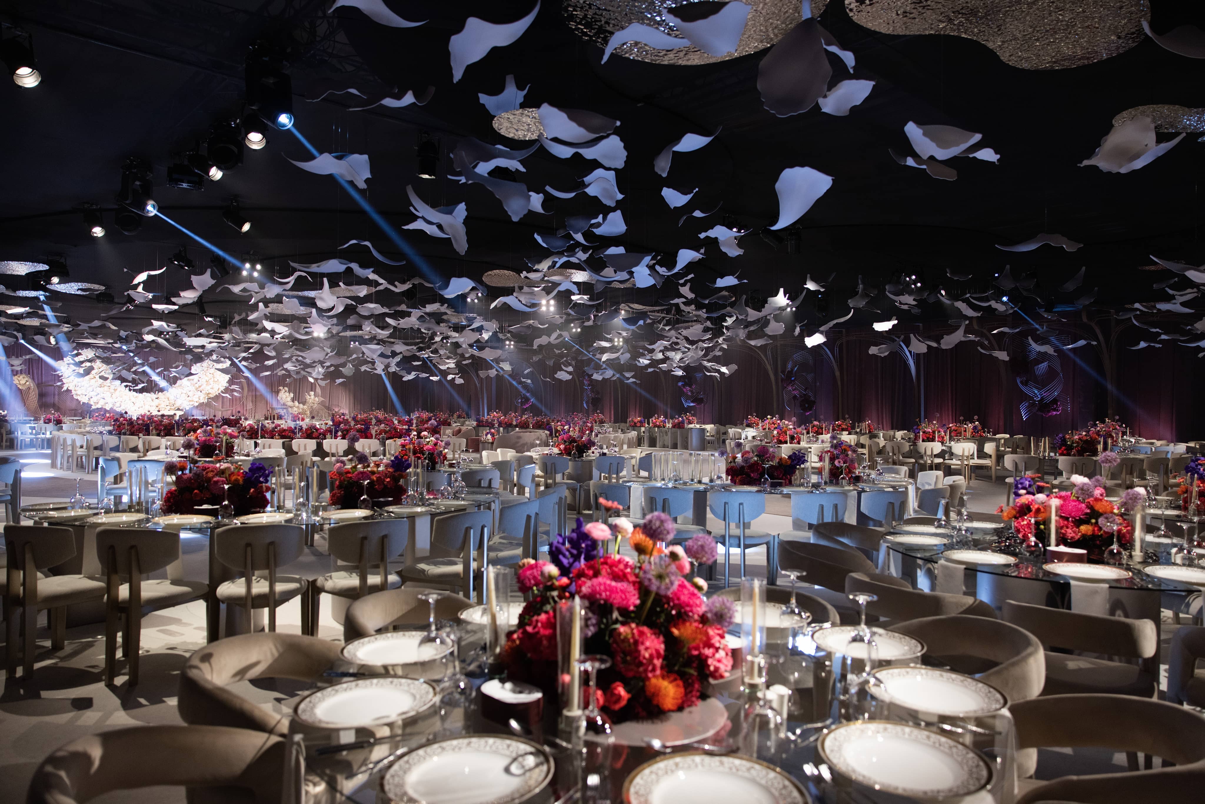 Wide view of the decorated event space with hanging sculptural elements and table settings.
